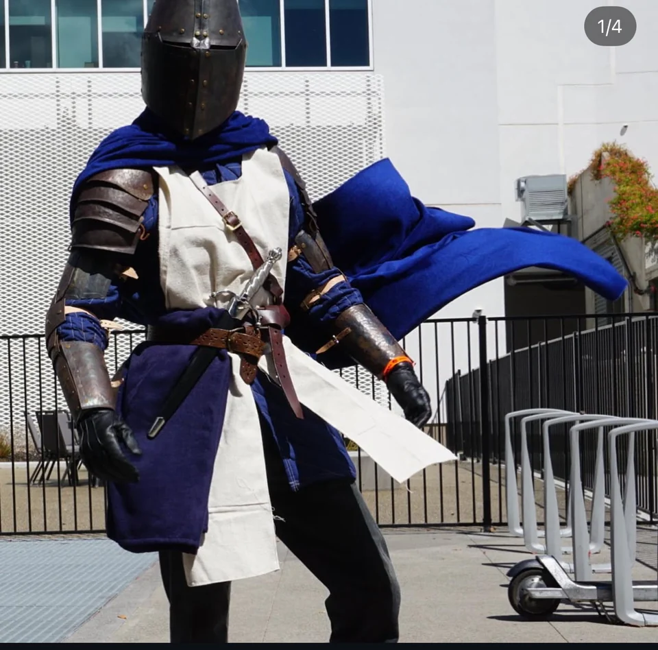 Blue and white Milanese armor outdoors holding a sword.