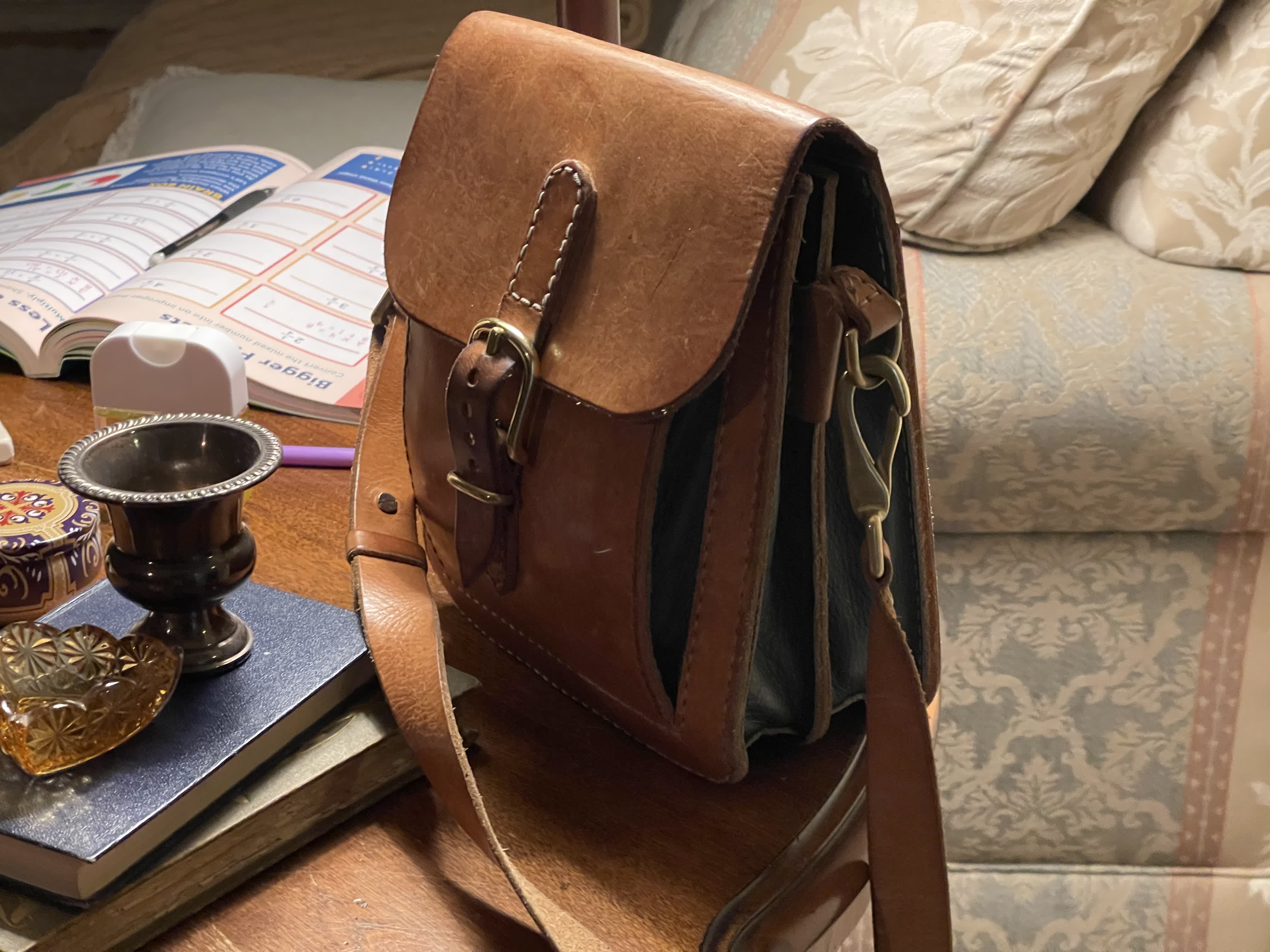 Handmade brown leather satchel on a tabletop.