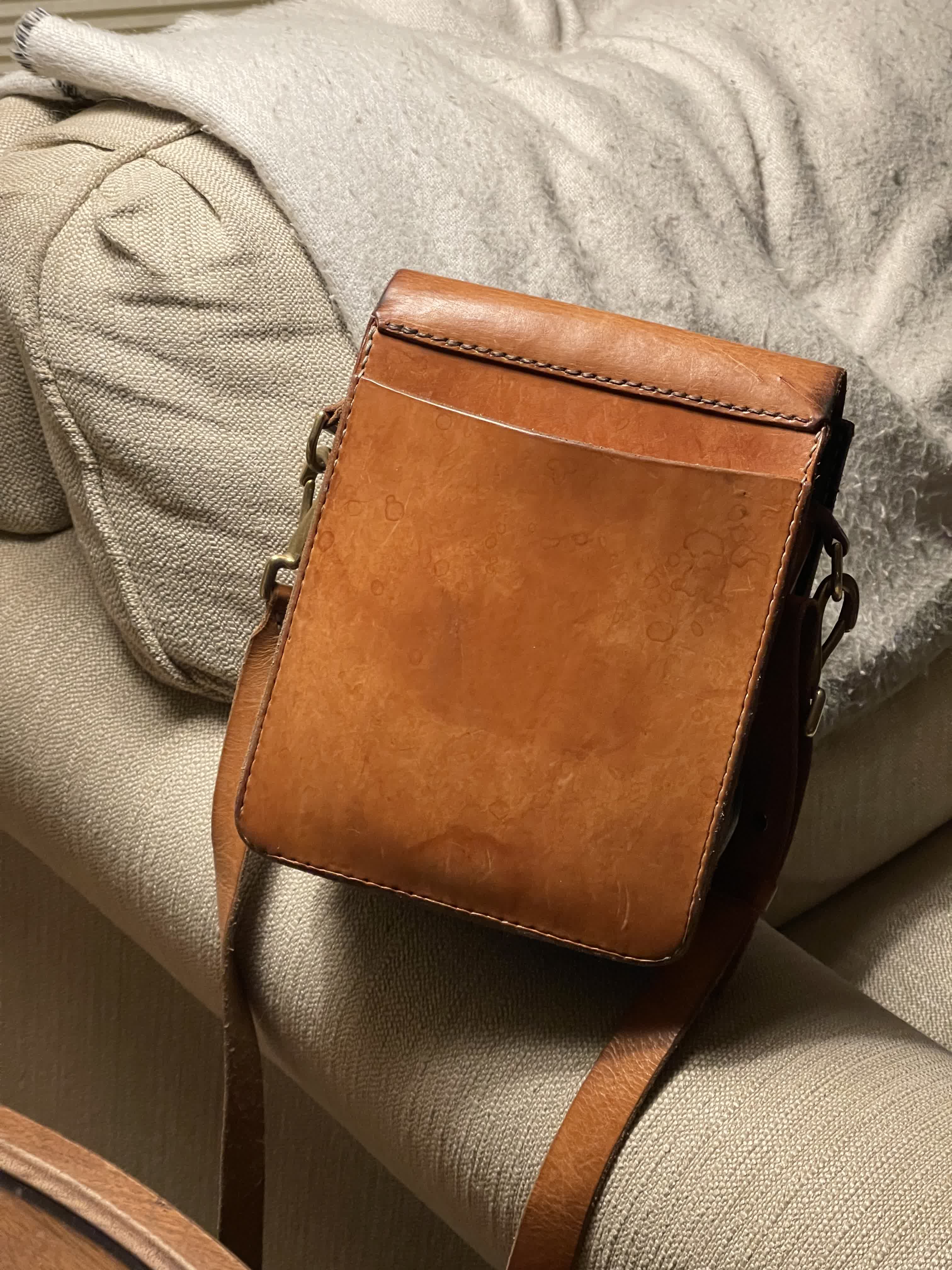 Front view of the brown leather satchel on a cushioned chair.