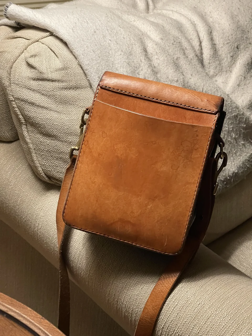 Front view of the brown leather satchel on a cushioned chair.